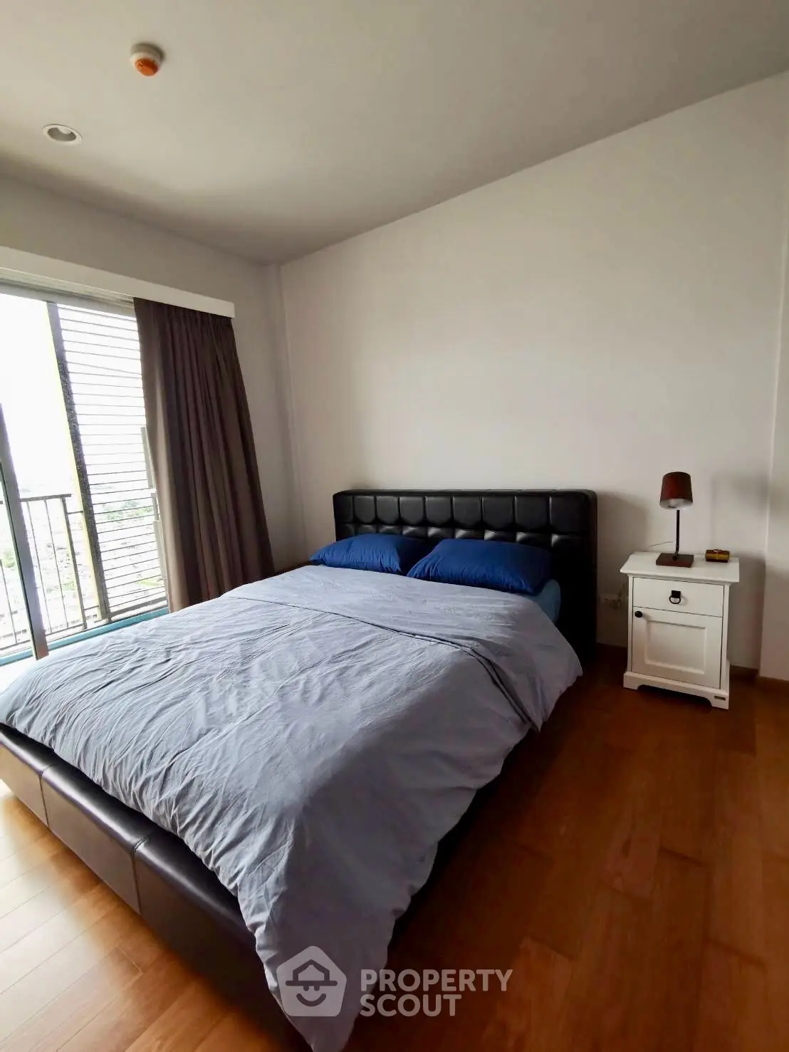 Cozy bedroom with modern furnishings and natural light from large window.