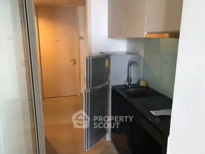 Compact modern kitchen with sleek cabinetry and stainless steel appliances in a cozy apartment.