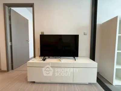 Modern living room with sleek TV stand and open door, showcasing minimalist design.