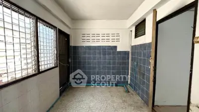 Spacious tiled room with large windows and secure metal grilles, ideal for versatile use.