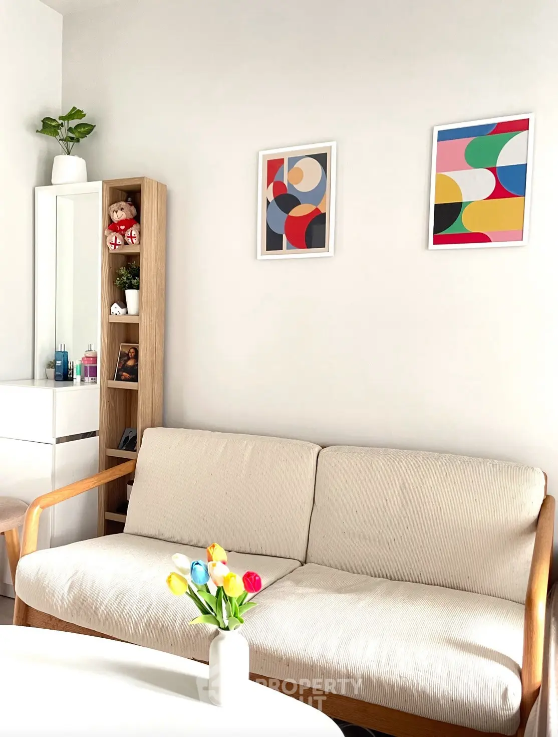 Bright living room with modern sofa, colorful wall art, and decorative shelving.
