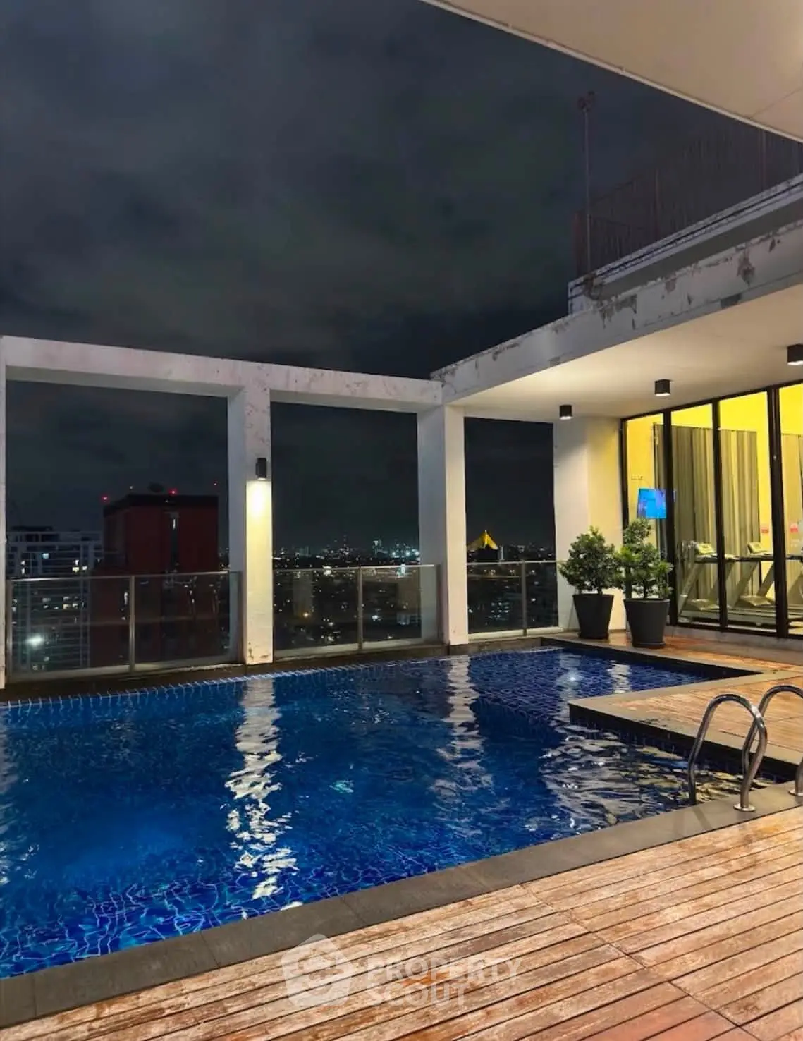 Luxurious rooftop pool with stunning city views at night, perfect for relaxation and entertainment.