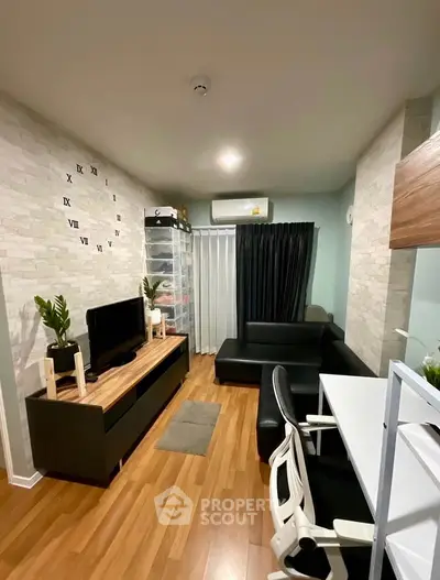 Modern living room with stylish decor and wooden flooring, featuring a sleek black sofa and entertainment unit.