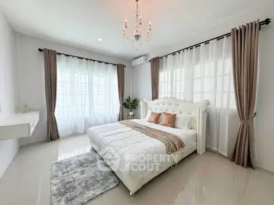 Luxurious bedroom with elegant chandelier and plush bed in a bright, airy space.