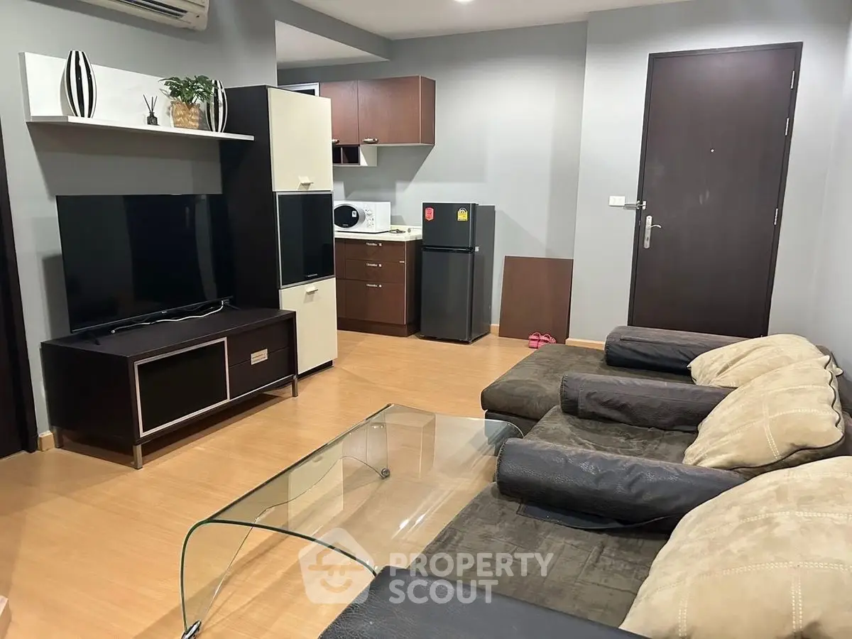 Modern living room with sleek furniture and compact kitchen area, perfect for urban living.