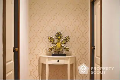 Elegant hallway interior with designer wallpaper and a chic console table adorned with a decorative vase, creating a welcoming ambiance in a luxurious home.