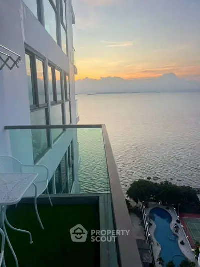 Stunning ocean view from high-rise balcony with glass railing and outdoor seating.