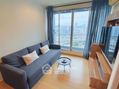 Modern living room with city view, featuring a sleek gray sofa and stylish decor.