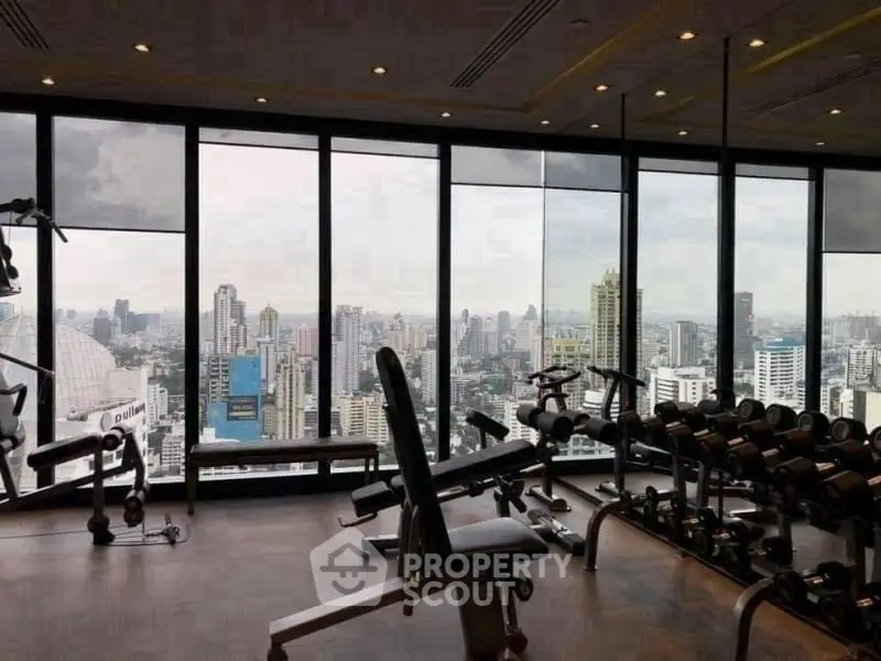 Luxurious gym with panoramic city skyline view and modern fitness equipment.