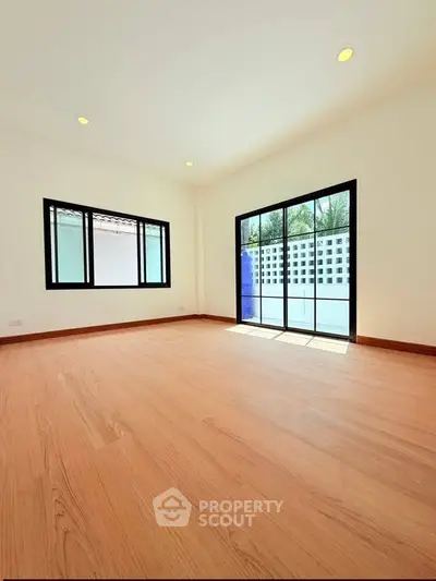Spacious sunlit room with large windows and wooden flooring, perfect for modern living.