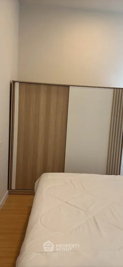 Modern bedroom with minimalist design and wooden sliding closet doors.