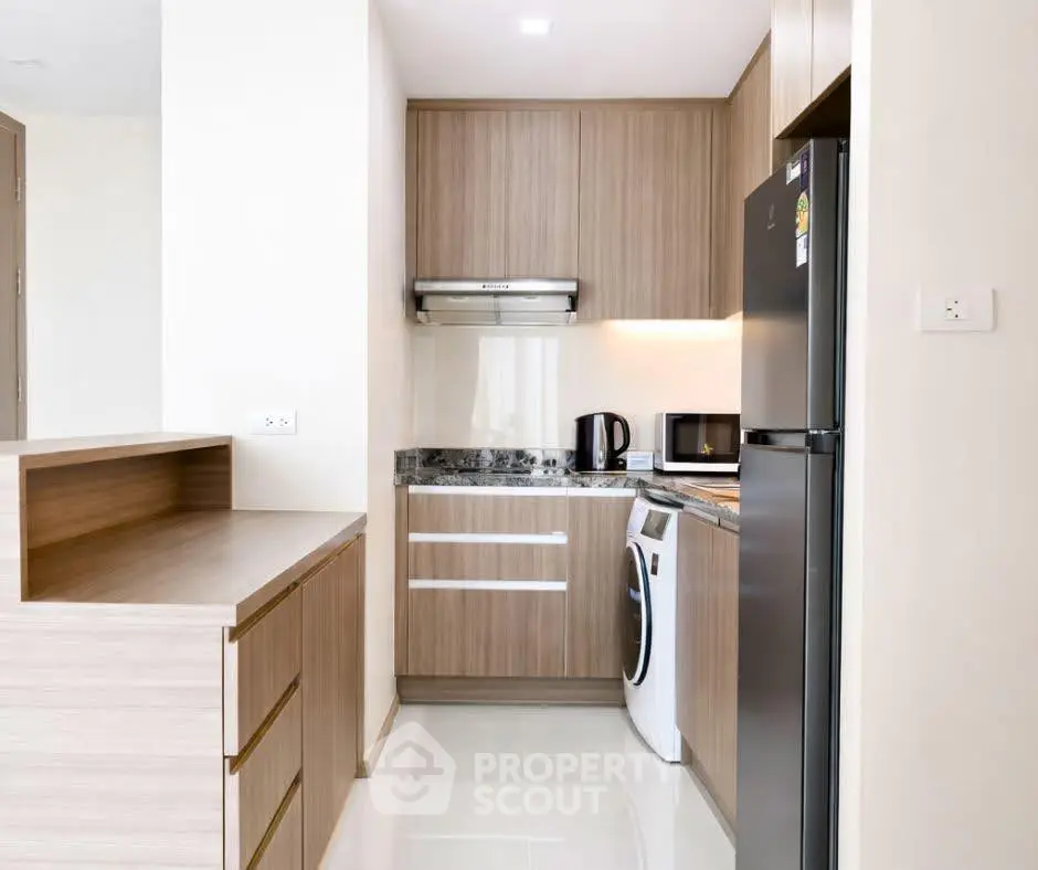 Modern kitchen with sleek appliances and wooden cabinetry in a compact layout.