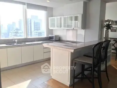 Spacious modern kitchen with city view, featuring sleek cabinetry and breakfast bar seating.