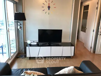 Modern living room with sleek TV stand and stylish wall clock, featuring a cozy balcony view.