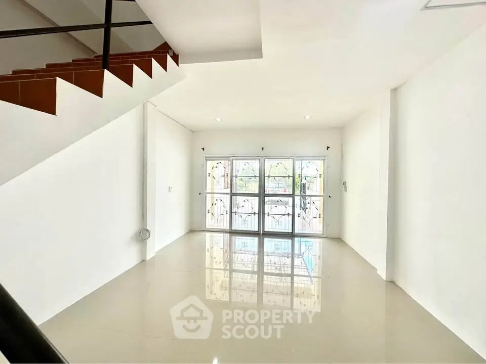Spacious unfurnished living room with large windows and glossy tile flooring.