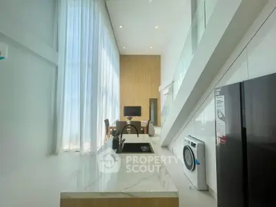 Modern open-plan kitchen with high ceilings and sleek appliances in a stylish apartment.