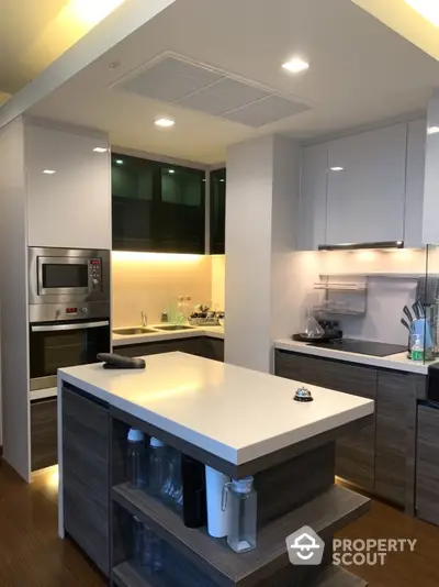 Modern kitchen with sleek design, featuring built-in oven and stylish island counter.