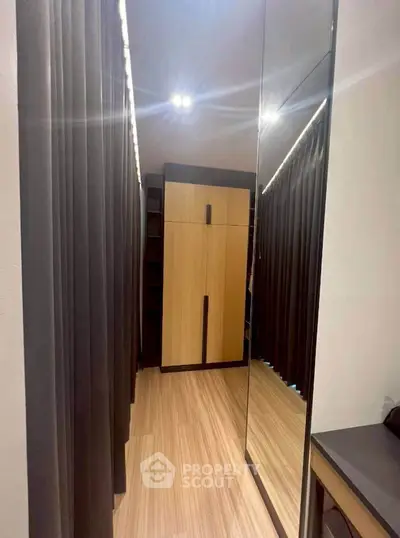 Modern walk-in closet with mirrored doors and sleek wooden flooring.
