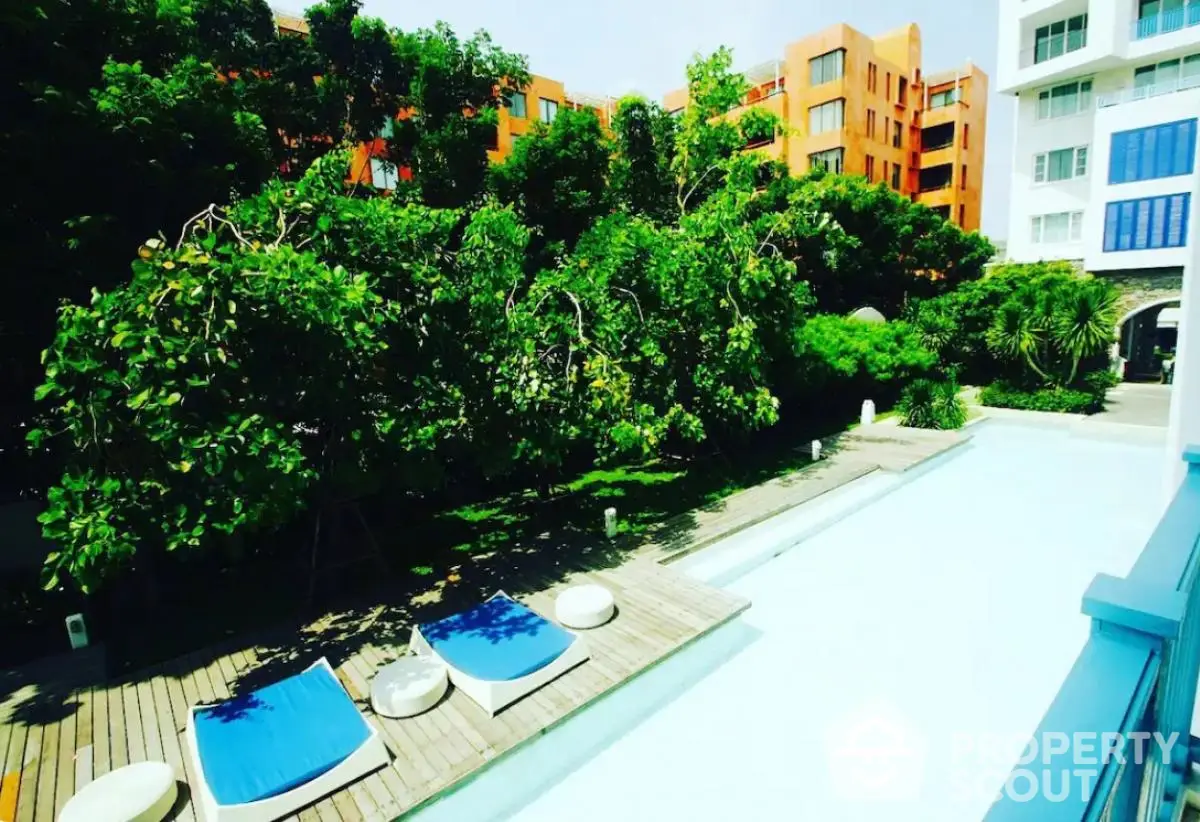 Luxurious poolside view with lush greenery and modern architecture in a serene residential complex.