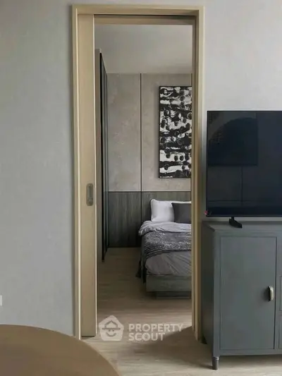 Modern bedroom view through open door with stylish decor and TV cabinet