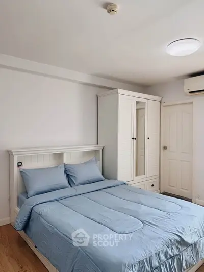 Cozy bedroom with blue bedding and white furniture, perfect for relaxation.