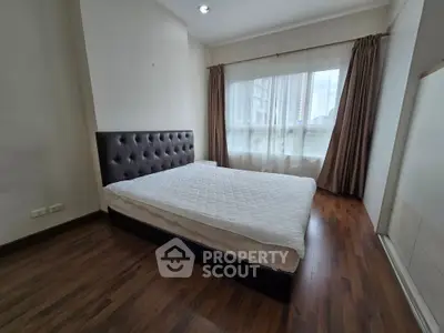 Spacious bedroom with large window and wooden flooring in modern apartment