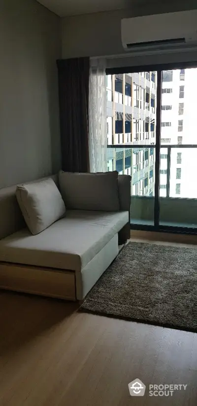 Modern living room with cozy sofa and city view balcony in a high-rise apartment.