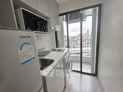 Compact kitchen with modern appliances and balcony view in urban apartment.
