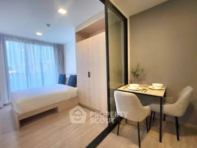 Modern studio apartment with cozy bedroom and dining area, featuring elegant decor and natural light.
