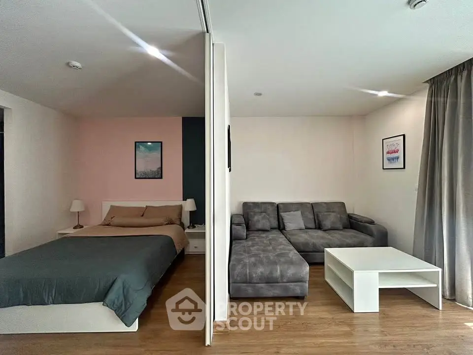 Modern studio apartment with cozy living area and stylish bedroom, featuring wooden flooring and contemporary decor.