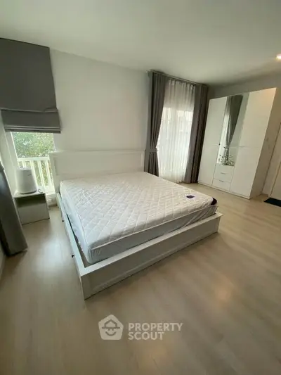 Spacious bedroom with modern decor and large windows for natural light.