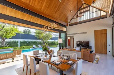 Luxurious open-plan living and dining area with pool view and high wooden ceilings.