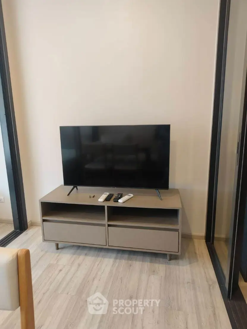 Modern living room with sleek TV stand and flat-screen TV on light wood flooring.