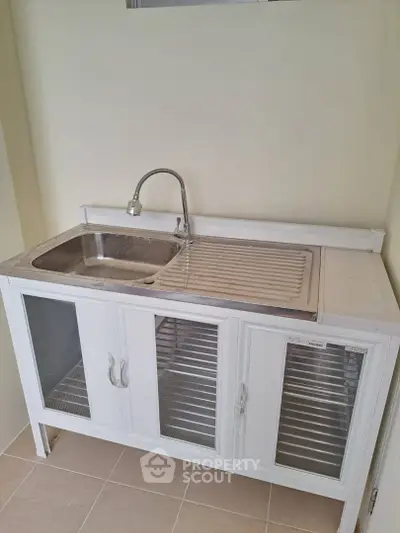Compact kitchen sink with modern faucet and glass cabinet doors, perfect for small spaces.