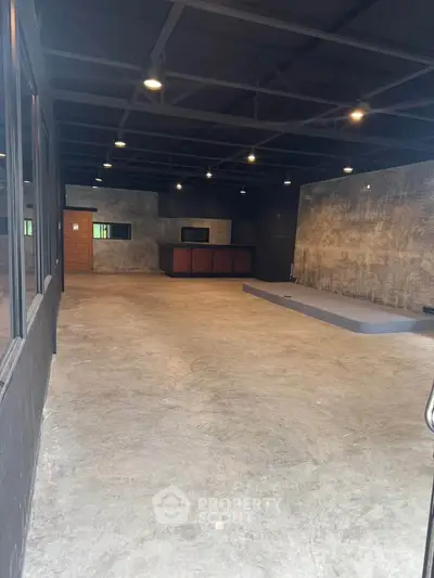 Spacious industrial-style interior with concrete floors and exposed ceiling, ideal for creative workspace or studio.