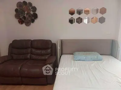 Cozy living space with leather sofa and modern bed, accented by stylish wall decor.