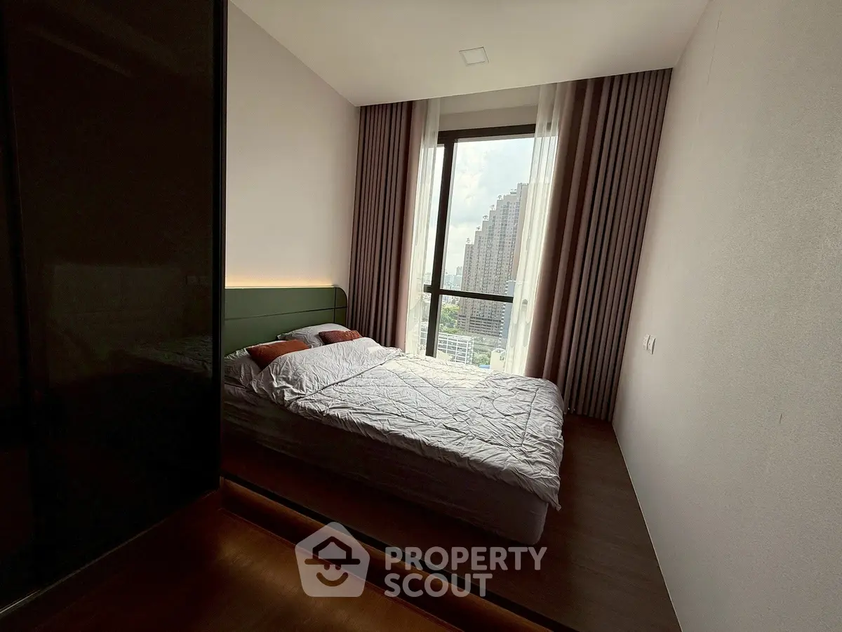 Modern bedroom with large window and city view, featuring minimalist design and cozy ambiance.