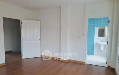 Spacious room with wooden flooring and adjacent bathroom with blue tiles.