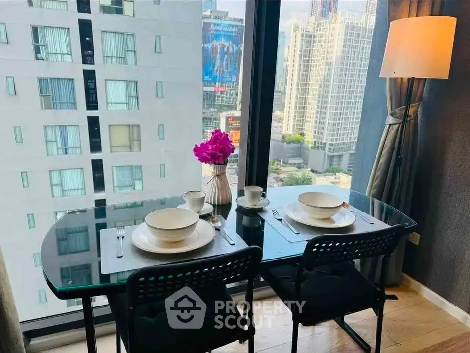 Modern dining area with city view, featuring a glass table set for two in a high-rise apartment.