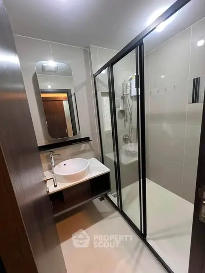Modern bathroom with sleek shower enclosure and stylish vanity in contemporary apartment.