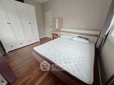 Cozy bedroom with wooden flooring and modern furniture, featuring a comfortable bed and spacious wardrobe.