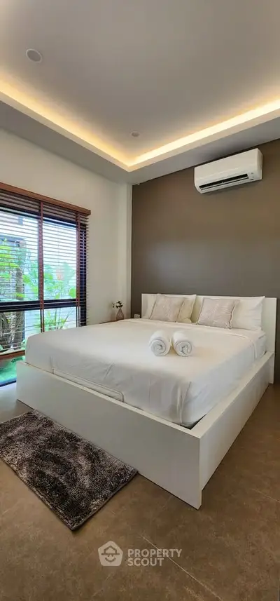Luxurious bedroom with modern decor and large window view, featuring a comfortable bed and air conditioning.