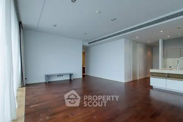 Spacious modern living room with hardwood floors and open kitchen layout.