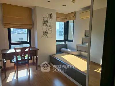 Cozy study room with wooden flooring and large windows offering city views.