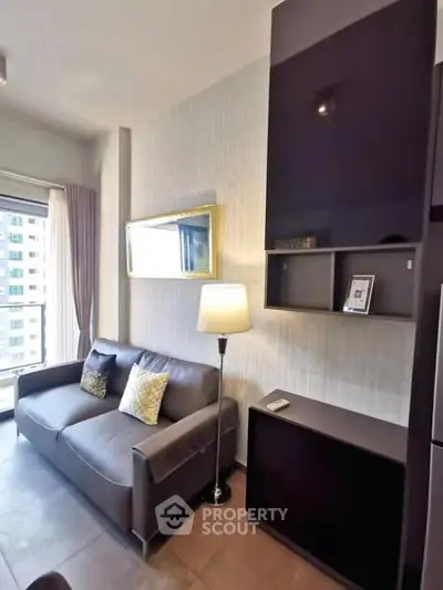 Modern living room with sleek furniture and large window offering city view.