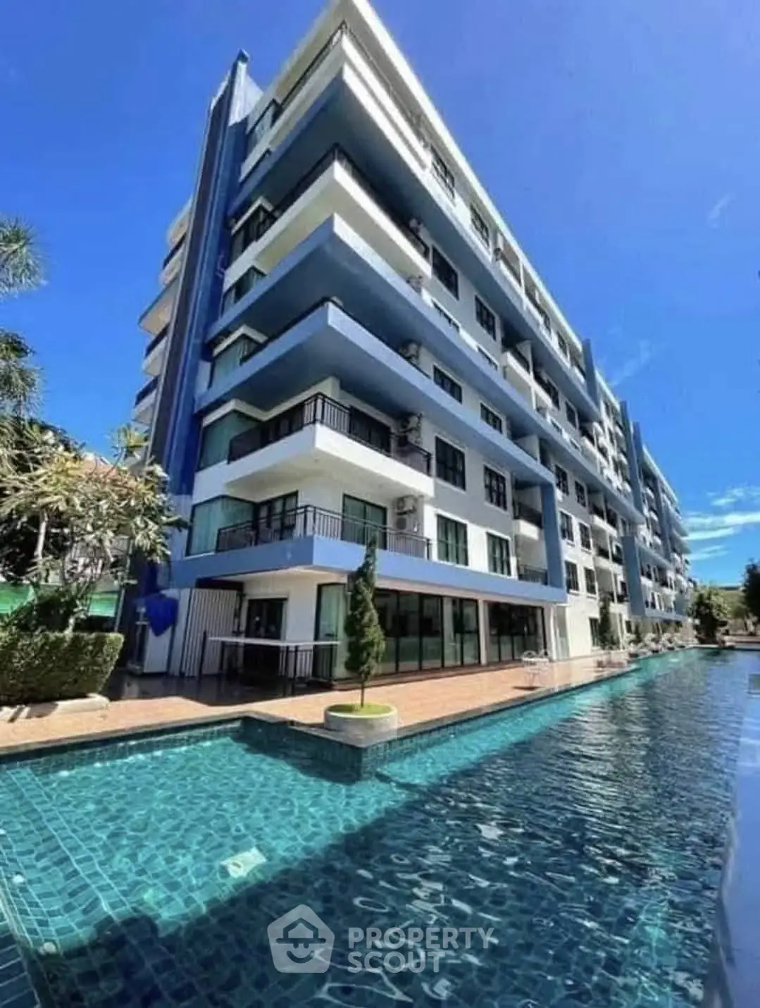 Modern apartment building with pool and balconies under clear blue sky.