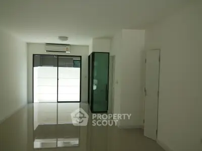 Spacious modern living room with glass doors and air conditioning in a minimalist apartment.