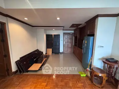 Spacious living area with wooden flooring and modern kitchen setup, ideal for comfortable living.