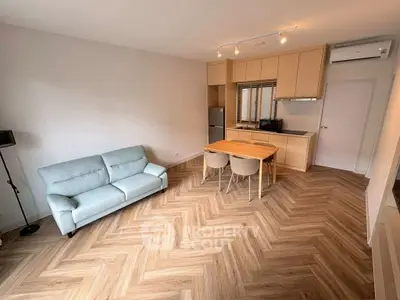 Modern living room with stylish herringbone flooring and open kitchen layout.