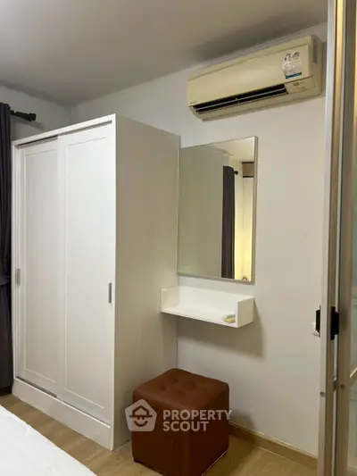 Modern bedroom with white wardrobe, mirror, and air conditioning unit